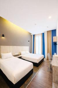 two beds in a hotel room with blue curtains at KARANG TIMUR Hotel in Kuantan