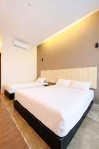 two beds in a hotel room with white sheets at KARANG TIMUR Hotel in Kuantan +2 photos