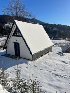 a small white barn with snow on the ground at Тиша in Verkhovyna