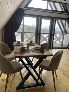 a table and chairs in a room with windows at Тиша in Verkhovyna