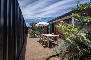 a wooden deck with a table and an umbrella at Spearwood Little Getaway in Spearwood