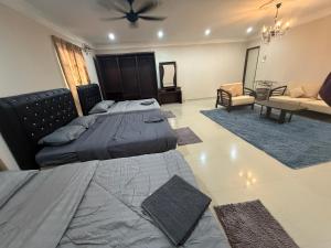 a bedroom with two beds and a living room at Megrram Homestay Ipoh-entire bungalow for 32 pax in Ipoh