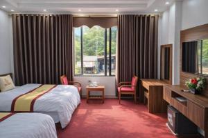 a hotel room with two beds and a desk at Friend Hotel Hà Giang in Ha Giang