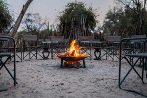 a fire in a pot on a table with chairs at Sian-simba-river-lodge in Victoria Falls