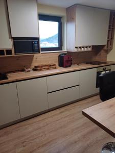 a kitchen with white cabinets and a microwave and a window at FLH - Trofeul Cerbului in Negrileşti