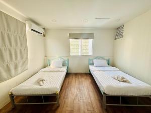 two twin beds in a room with a window at BKK Rama3 Guest House in Bangkok