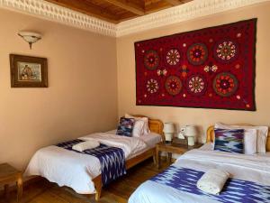 two beds in a room with a red painting on the wall at Salom Inn in Bukhara