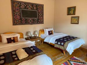 a room with two beds and a picture on the wall at Salom Inn in Bukhara +11 photos