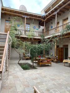 an outdoor patio with tables and benches in a building at Salom Inn in Bukhara