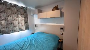 a small bedroom with a blue bed and a window at Camping Les Palmiers in Hyères +35 photos