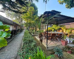 an outdoor restaurant with tables and an umbrella at Chitwan Forest Resort with swimming pool , Chitwan National Park in Sauraha