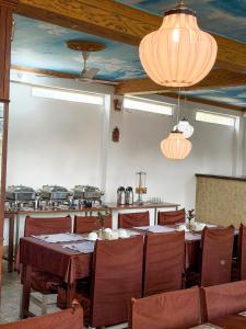 a dining room with tables and chairs and a kitchen at Chitwan Forest Resort with swimming pool , Chitwan National Park in Sauraha