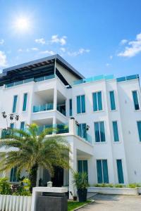 a white building with a palm tree in front of it at KARANG TIMUR Hotel in Kuantan