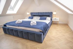 a bedroom with a large blue bed in a attic at Apartmány Harmony Liptov - City Center & Private Wellness in Liptovský Mikuláš
