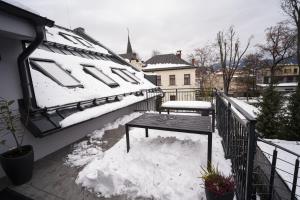 a snow covered balcony with a bench in the snow at Apartmány Harmony Liptov - City Center & Private Wellness in Liptovský Mikuláš