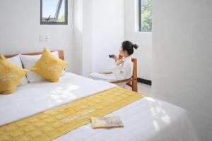 a woman sitting in a chair taking a picture of a bed at Kim Hoàn Hotel Phan Rang in Phan Rang–Tháp Chàm