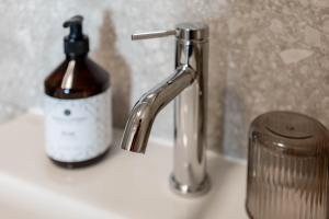 ein Waschbecken im Badezimmer mit einem Seifenspender neben einer Flasche Seife in der Unterkunft Karlingerhaus Hotel Hostel Home in Königswiesen
