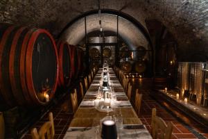 a long table in a wine cellar with wine barrels at Sipos Borház és Vendégház in Badacsonyörs