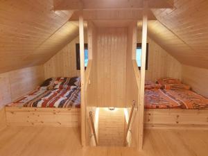two beds in a small room with wooden walls at Chata Mína in Smržovka