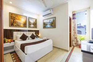 a bedroom with a large white bed with paintings on the wall at Hotel Warm Welcome Inn Noida Sector 51 in Noida +44 photos