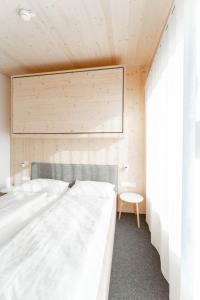 ein Schlafzimmer mit einem großen weißen Bett und einem Stuhl in der Unterkunft Karlingerhaus Hotel Hostel Home in Königswiesen