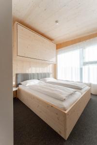 ein großes Holzbett in einem Zimmer mit Fenster in der Unterkunft Karlingerhaus Hotel Hostel Home in Königswiesen