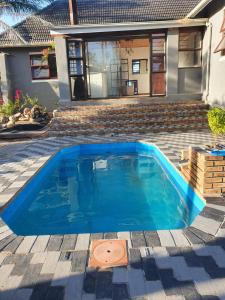 a blue swimming pool in front of a house at Ludiz Self Catering Accommodation in Avondale