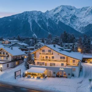 a house in the snow with mountains in the background at Seelos - Alpine Easy Stay - Bed & Breakfast in Mieming