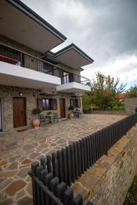 a house with a stone patio and a fence at Monastiri Mountain Escape in Konitsa