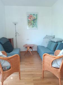 a living room with a blue couch and two chairs at Gästehaus am Main in Randersacker