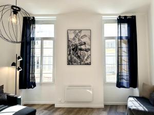 a living room with two windows and a picture on the wall at LE WLÉRICK LUMINEUX - Spacieux - Hyper Centre in Mont-de-Marsan