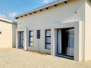 a white house with large windows and a driveway at The Botik Hides in Mogwase