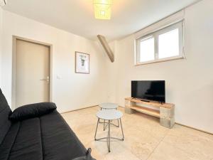 a living room with a couch and a tv at Le Ronsard - Élégance - Central in Mont-de-Marsan