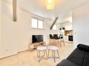 a living room with a couch and a tv and chairs at Le Ronsard - Élégance - Central in Mont-de-Marsan