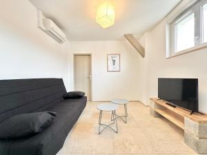 a living room with a black couch and a flat screen tv at Le Ronsard - Élégance - Central in Mont-de-Marsan +9 photos