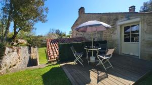 a wooden deck with a table and an umbrella at ENTRE PIERRE ET BOIS in Saint-Savinien