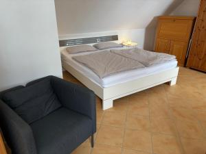 a bedroom with a bed and a chair at Ferienwohnung mit Küche und Bad in Hollenbach