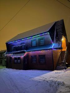 a house with christmas lights on the side of it at U Janiny in Czarna Góra