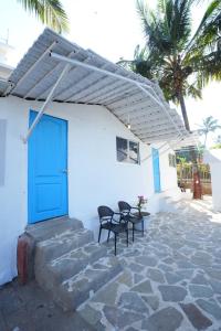 a blue door on a white building with chairs at Beachouse Beachfront Cottages And Suites in Calangute