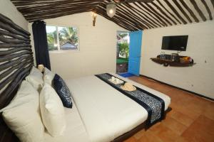 a bedroom with a large white bed with a television at Beachouse Beachfront Cottages And Suites in Calangute