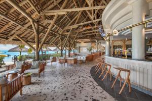 ein Restaurant mit Tischen und Stühlen und einer Bar in der Unterkunft Paradis Beachcomber Golf Resort & Spa in Le Morne