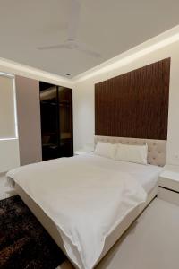 a bedroom with a large white bed with a wooden headboard at Supremo Home Stays in Agra
