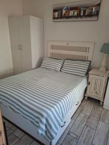a bedroom with a bed with a blue and white striped blanket at Uvongo Sea Scapes Holiday Apartment in Margate +15 photos