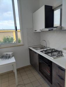 a kitchen with a stove and a sink and a window at Petit Appartament in Policoro