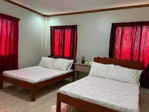 two beds in a room with red curtains at Pableo's Pension House in Moalboal in Moalboal