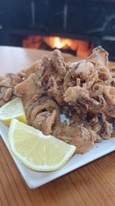 ein Teller frittierte Calamari mit einer Zitronenscheibe in der Unterkunft Posada Ojedo Los Ñeros in Ojedo