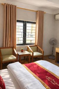 a hotel room with two beds and chairs and a window at Candy Hotel Hạ Long in Ha Long