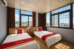 two beds in a room with large windows at Candy Hotel Hạ Long in Ha Long
