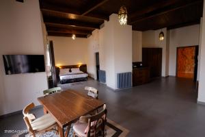 a living room with a wooden table and a bed at Domaine de Chouchene in Şaḩrat al Qashsh