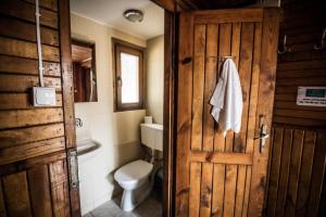 a bathroom with a toilet and a wooden door at Leśna Ryba I Domki nad jeziorem z parkiem linowym in Jedlanka Stara +21 photos